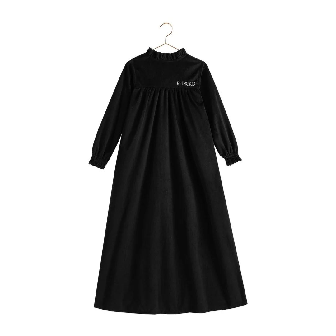 The back view of the black velvet RetroKid Isla maxi dress, highlighting its smooth, sweeping drape.