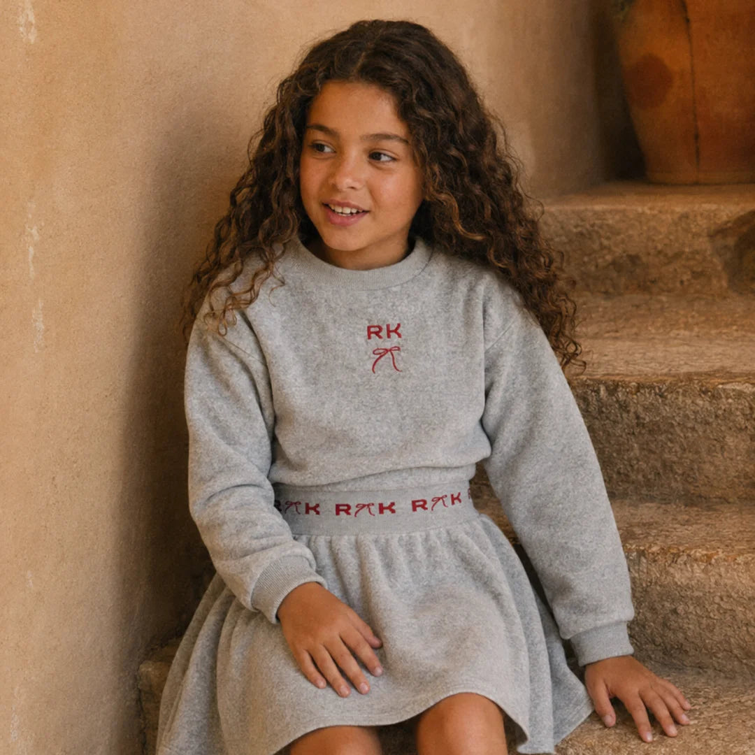 A little girl sitting wearing the bold gray and red RetroKid scuba dress.