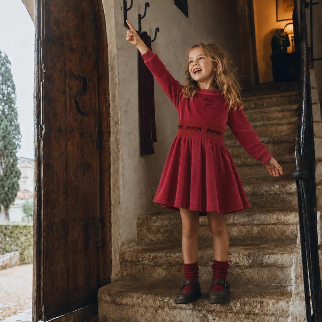 A young girl happily playing while wearing the structured red RetroKid scuba dress.