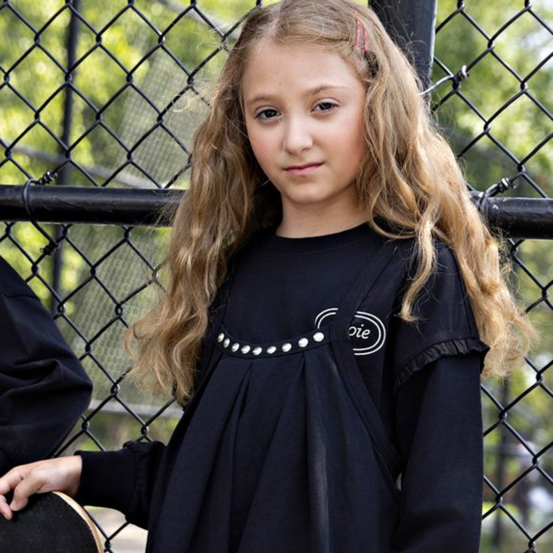 A child wearing the Rooie and Friends black sweatshirt during an outdoor playground adventure.