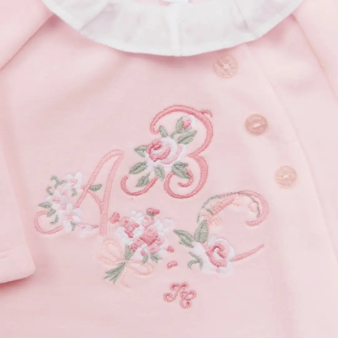 Pink garment with embroidered initials and floral designs