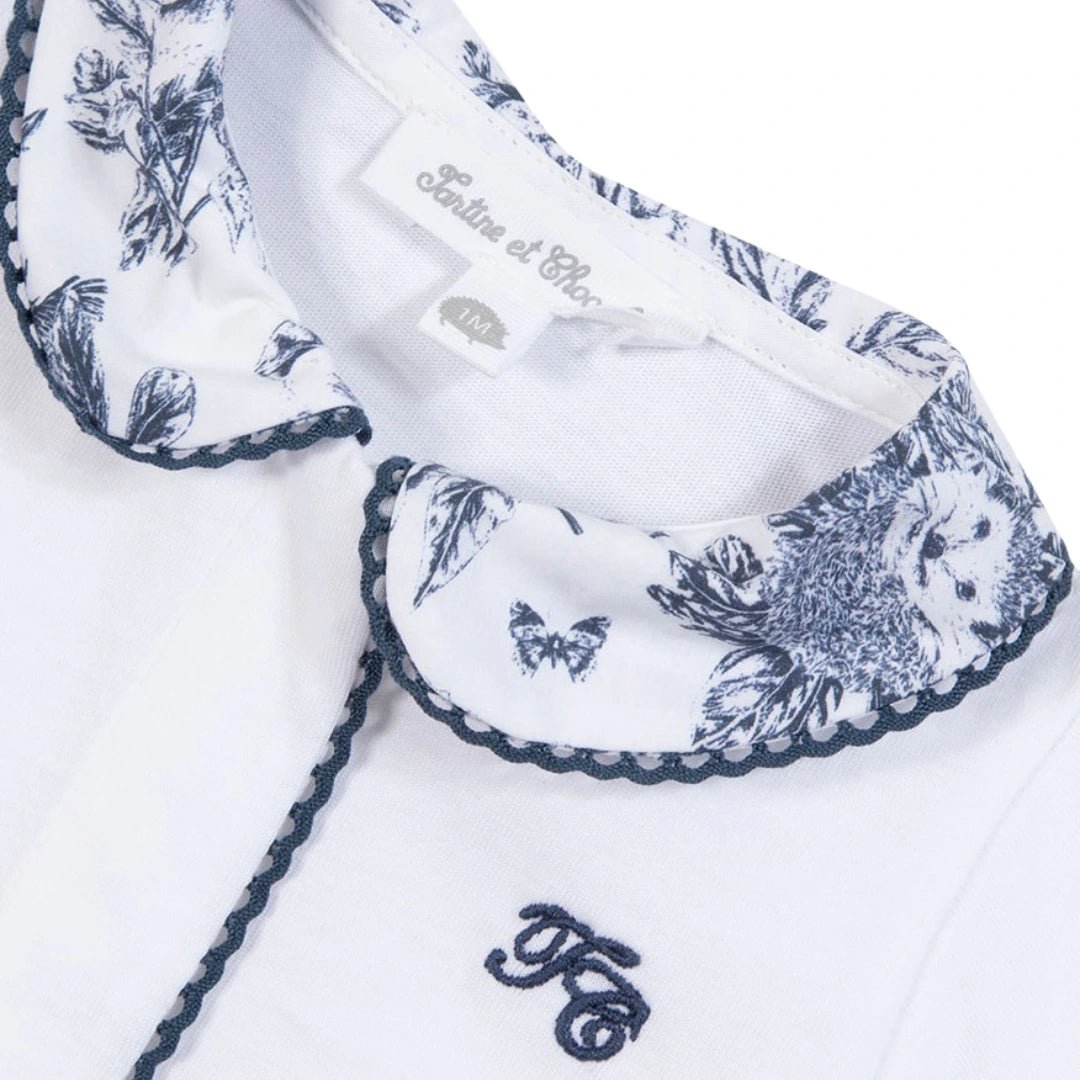 White fabric with blue floral embroidery and a visible brand label on a white background