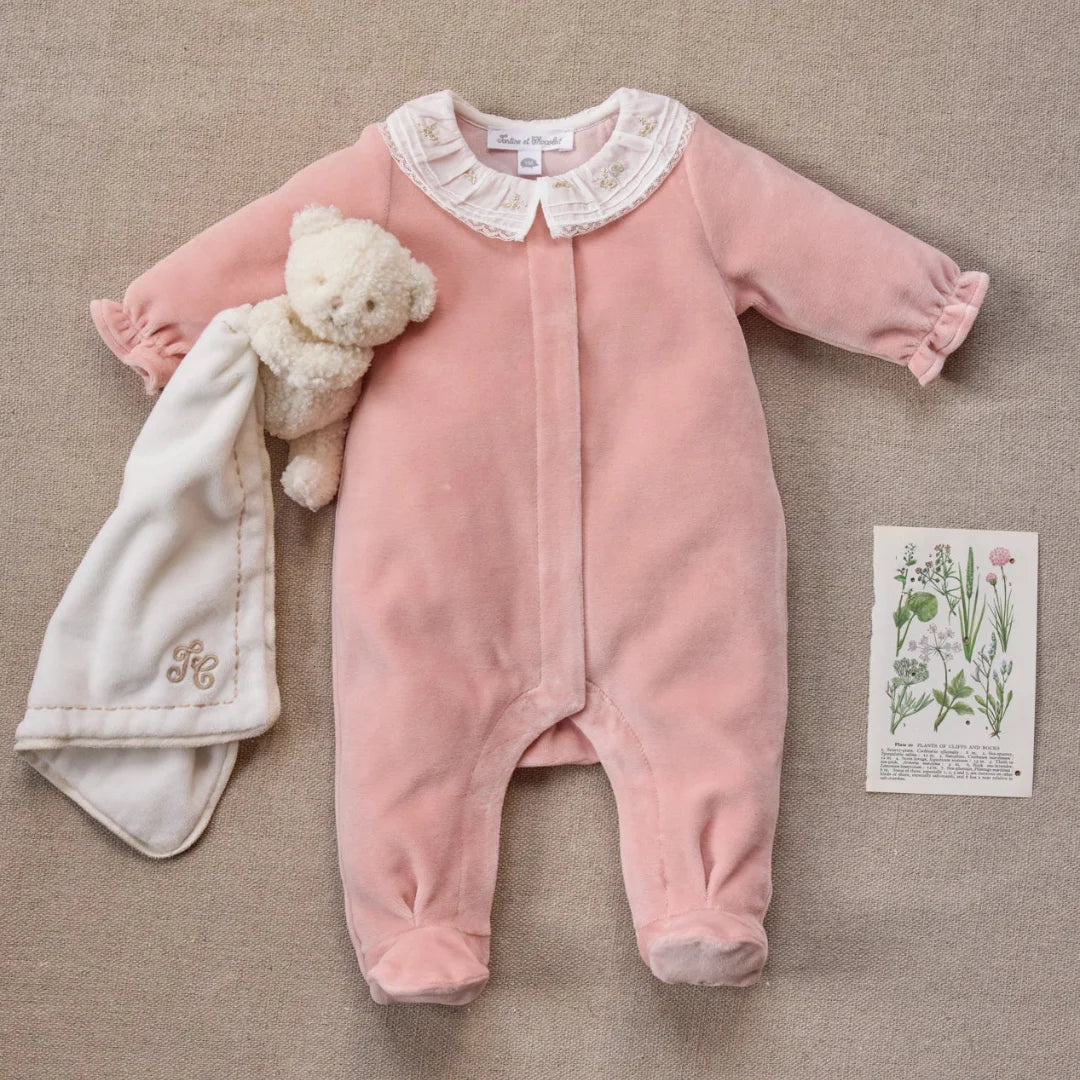 A newborn baby wearing the Tartine et Chocolat peach footie comfortably during a quiet nap.