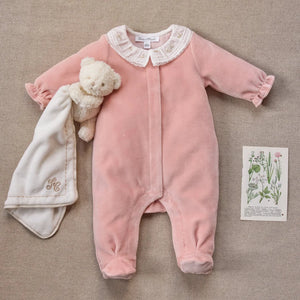 A newborn baby wearing the Tartine et Chocolat peach footie comfortably during a quiet nap.