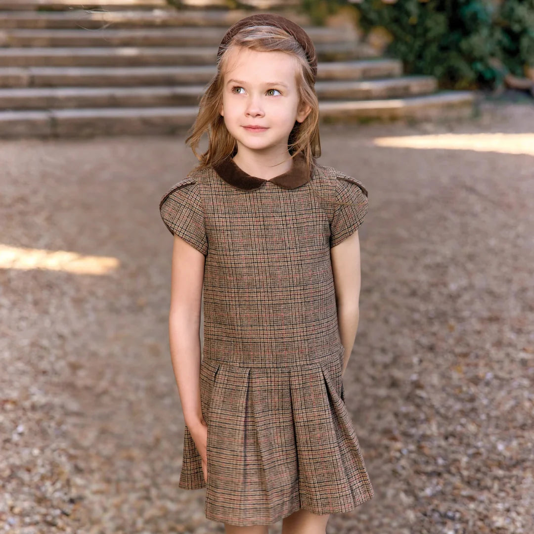 A child wearing the Tartine et Chocolat brown dress comfortably during a family holiday outing.