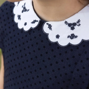 A high-resolution close-up of the wool fabric texture and scalloped collar details.