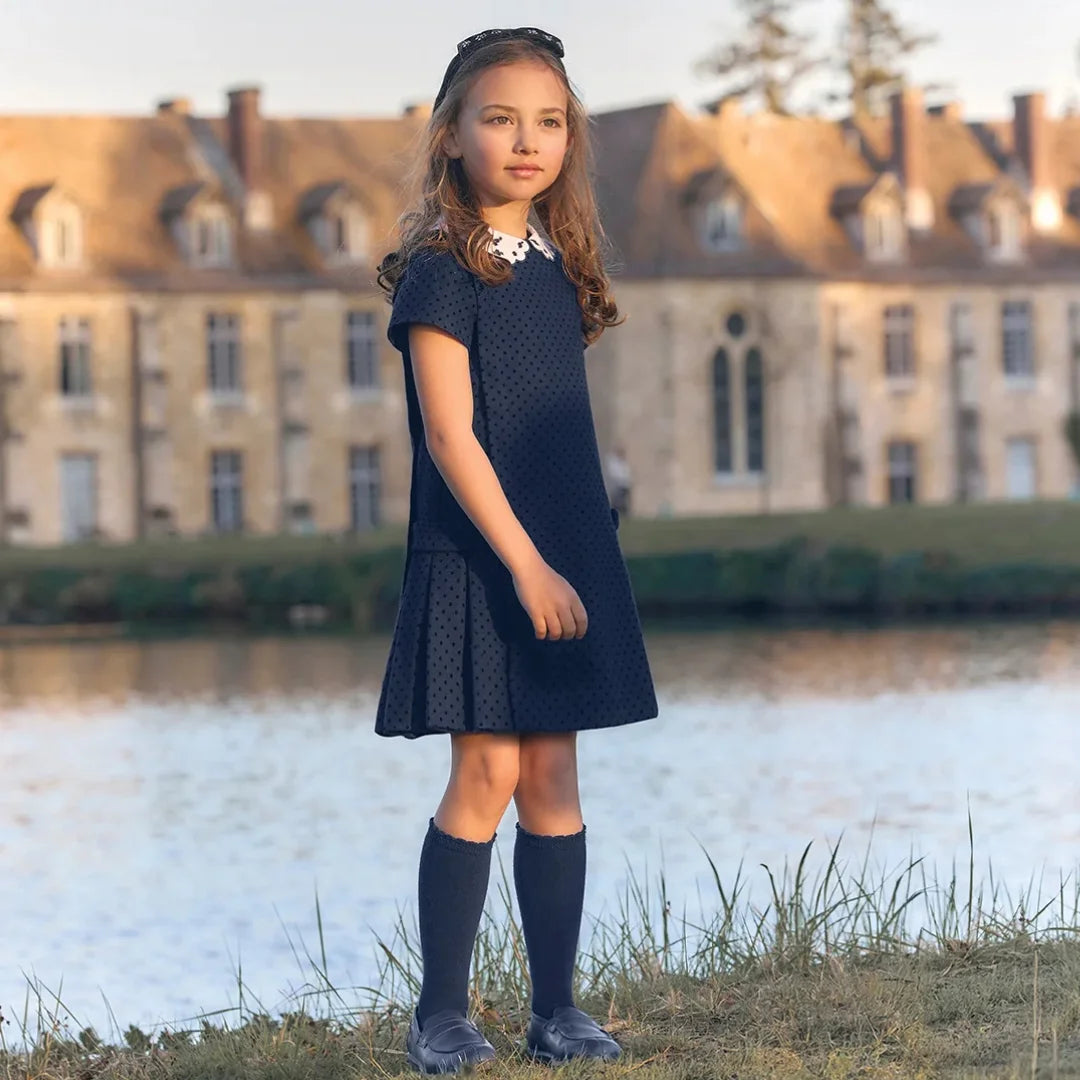 A child wearing the Tartine et Chocolat navy wool dress comfortably during a family holiday outing.