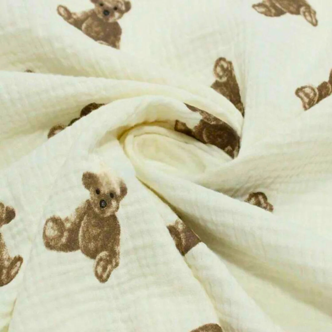 A high-resolution close-up of the soft organic cotton muslin texture and teddy bear illustration.