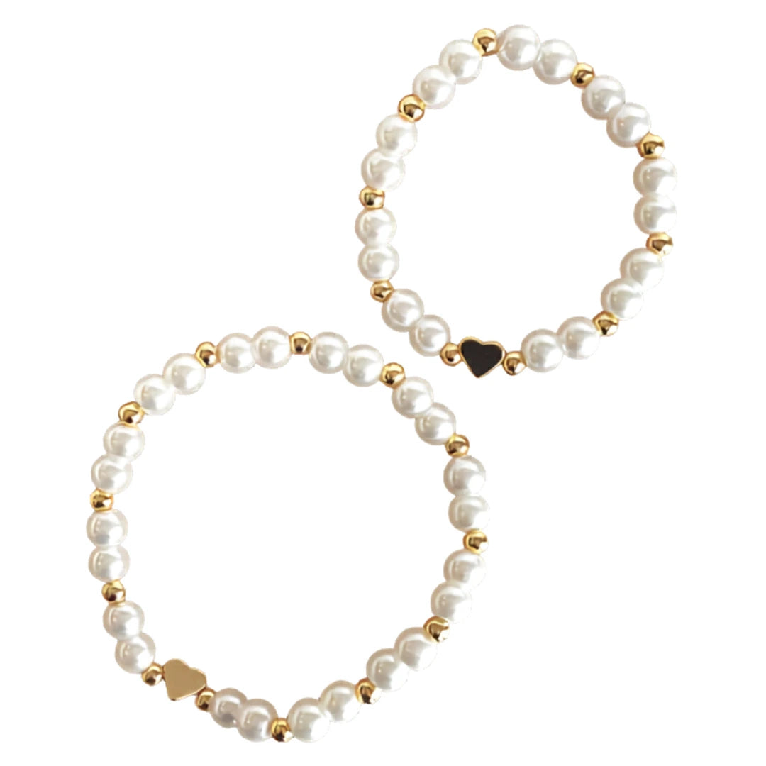 A breathtaking mini bracelet featuring a string of luminous white pearls and a polished architectural gold heart charm.