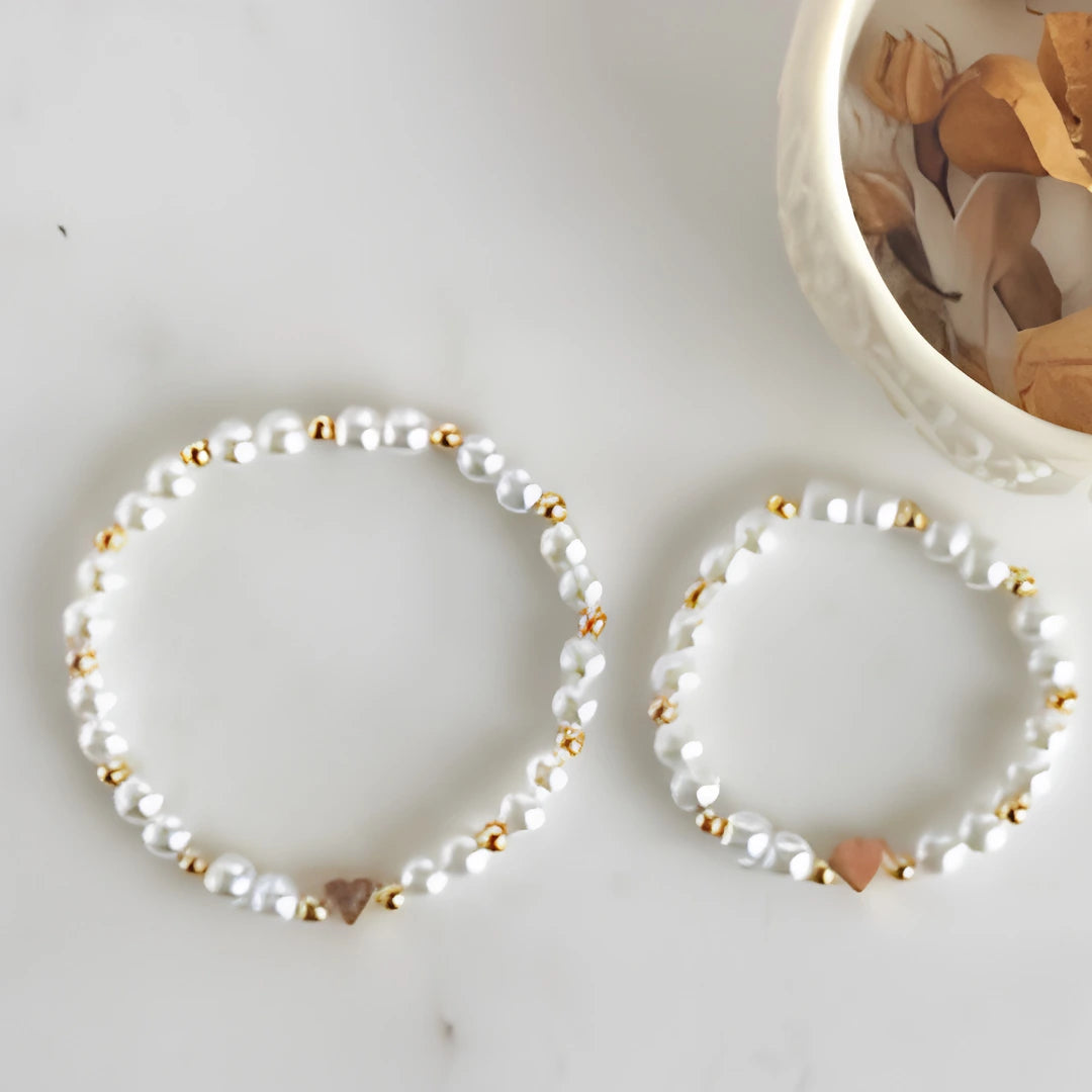 Two pearl bracelets with gold accents on a light surface.